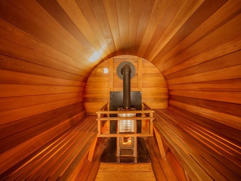 Warm cedar interior of a dry barrel sauna with heater and benches